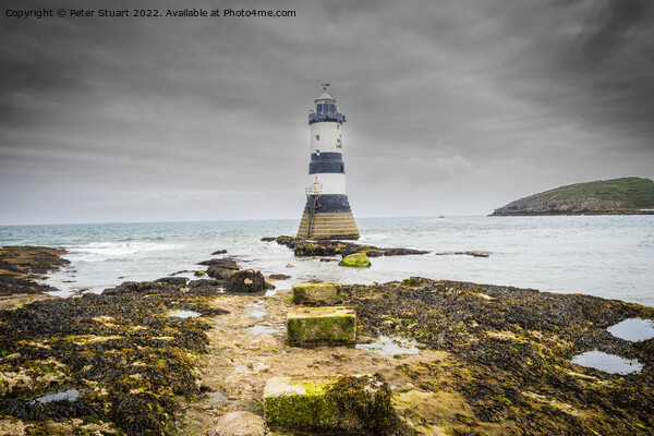 Penmon lighthouse sits at the start of the Menai Strait across f Picture Board by Peter Stuart
