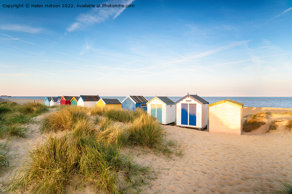 Colourfull beach huts in the sand dunes at Southwold Picture Board by Helen Hotson