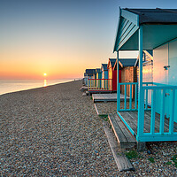 Buy canvas prints of Stunning sunset over seaside beach huts  by Helen Hotson