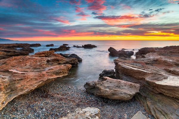 Stunning sunrise over the beach and rocks at Torre de la Sal  Picture Board by Helen Hotson