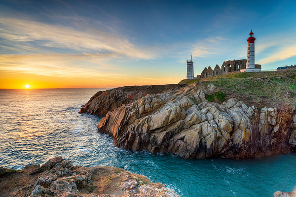 Sunset over the lighthouse at Pointe Saint Mathieu Picture Board by Helen Hotson
