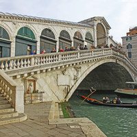 Buy canvas prints of A gondola going under the Rialto Bridge on the Gra by John Keates