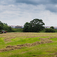 Buy canvas prints of A Virgin train passes a tractor on a field by Jason Wells