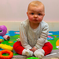 Buy canvas prints of A baby girl sitting on a colourful mat with her toys by Gregory Culley