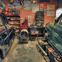 Buy canvas prints of  Vintage cars in a garage for repair by Mal Bray