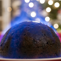 Buy canvas prints of Christmas Pudding on a table, with a Christmas tre by Dave Carroll