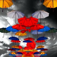 Buy canvas prints of colorful umbrellas against a stormy sky by ken biggs