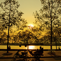 Buy canvas prints of Sunset and Tuk Tuk driver of Kampot, Cambodia by Julian Bound