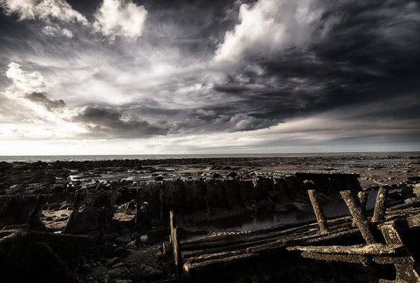 Storm clouds over beached shipwreck Picture Board by Simon Bratt LRPS