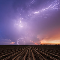 Buy canvas prints of Lightning crawler over a ploughed field at sunset by John Finney