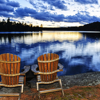 Buy canvas prints of Wooden chairs at sunset on lake shore by ELENA ELISSEEVA