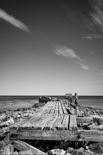 Old breakwater at Lossiemouth beach in Mono Picture Board by Joe Dailly