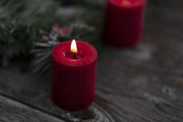 Close up of single red glowing candle with fir and wood dark bac Picture Board by Thomas Baker