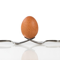 Buy canvas prints of Isolated whole brown egg balanced on two forks by Thomas Baker