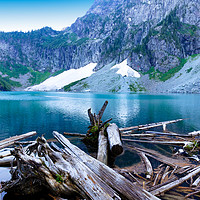 Buy canvas prints of Log jam in front of glacier lake with mountains an by Thomas Baker