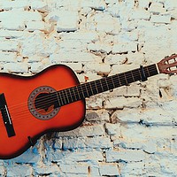 Buy canvas prints of Common Guitar On White Brick Wall by Radu Bercan