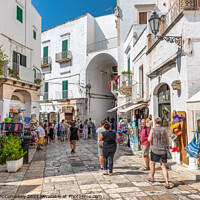 Buy canvas prints of Tourists on Via Cattedrale in Ostuni, Italy by Angus McComiskey