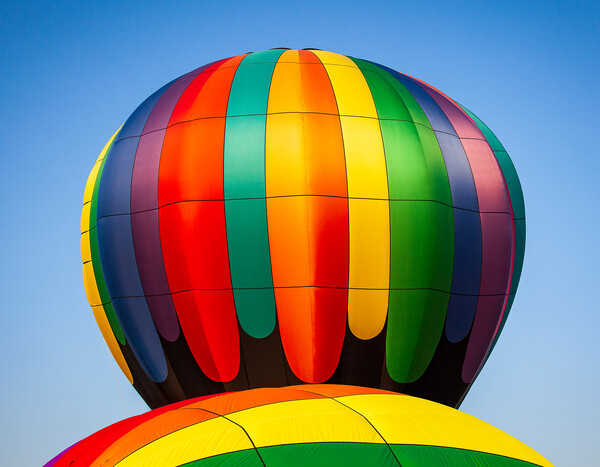 Colorful hot air balloon rising above another with Picture Board by Steve Heap