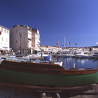 Buy canvas prints of Green boat under dramatic sunny noon in St. Tropez by Alfredo Bustos
