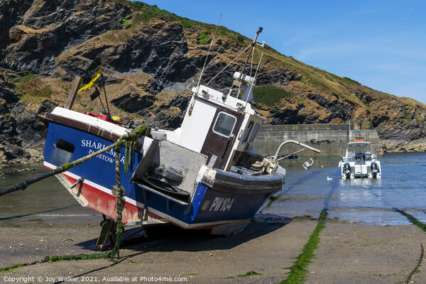 A fishing boat anchored in Port Isaac bay Picture Board by Joy Walker