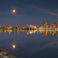 Buy canvas prints of The moon and cityscape lights, reflect off harbour by Alan Hill