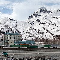 Buy canvas prints of The Begich Towers Condominium building and snow covered mountains behind, Whittier, Alaska, USA by Dave Collins