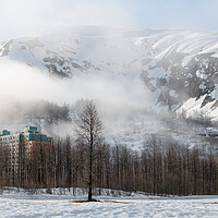 Buy canvas prints of Mist and Fog swirls around Begich Towers Condominium building and the mountains behind, Whittier, Alaska, USA by Dave Collins