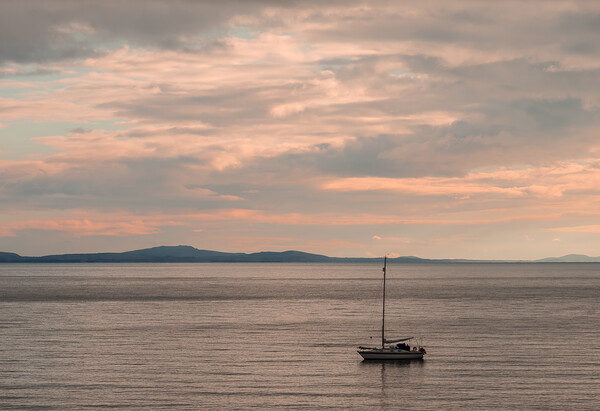Sailboat moored off the coast at Aberffraw. Picture Board by Colin Allen