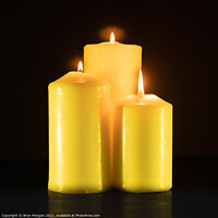 Buy canvas prints of Three burning candles in the darkness by Bryn Morgan