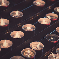 Buy canvas prints of Rows of brightly burning votive candles by Marco Bicci