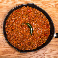 Buy canvas prints of Chili in Black Pan on Wood Table with Jalapeno Pep by Darryl Brooks