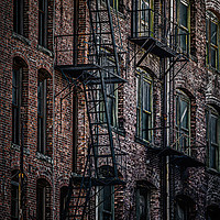 Buy canvas prints of Wrought Iron Fire Escapes in Brick Alley by Darryl Brooks