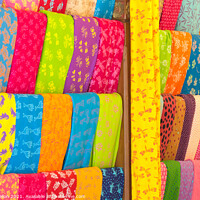 Buy canvas prints of Bolts of colourful cloth hanging in a shop in Denpasar, Bali, In by Kevin Hellon