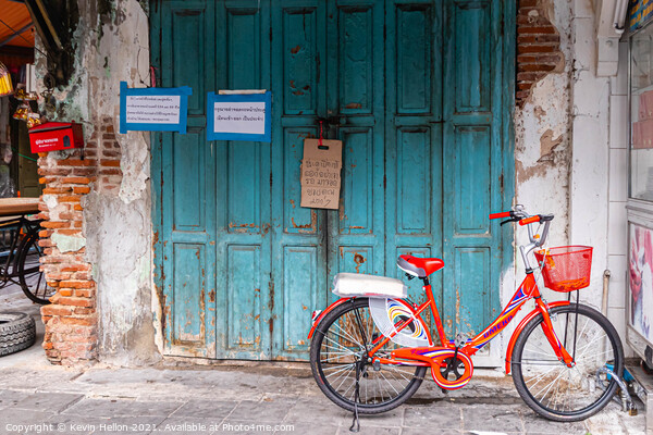 Red bicycle parked by blue doors Picture Board by Kevin Hellon