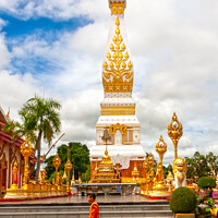 Buy canvas prints of A monml walks past the spire in Wat Phra That Phanom by Kevin Hellon