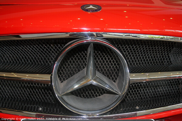 Mercedes badge on a red car. Picture Board by Kevin Hellon