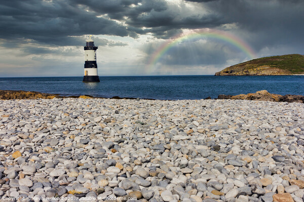 Penmon lighthouse and shingle beach with rainbow Picture Board by Kevin Hellon