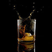 Buy canvas prints of Splash in glass of whiskey and ice by Chris Willemsen