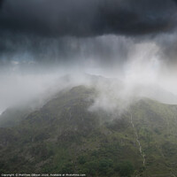 Buy canvas prints of Dramatic landscape image of storm clouds hanging over Snowdonia mountain range with heavy rainfall in Autumn with misty weather by Matthew Gibson