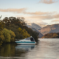 Buy canvas prints of Landscape image of boat moored on Ullswater in Lake District with snowcapped mountains in background with beautiful vibrant Autumn Fall colors by Matthew Gibson
