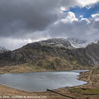 Buy canvas prints of Beautiful moody Winter landscape image of Llyn Idwal and snowcapped Glyders Mountain Range in Snowdonia by Matthew Gibson