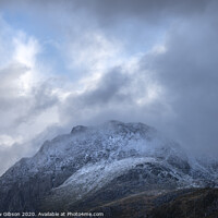 Buy canvas prints of Stunning moody dramatic Winter landscape image of snowcapped Tryfan mountain in Snowdonia with stormy weather brooding overhead by Matthew Gibson