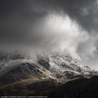 Buy canvas prints of Stunning moody dramatic Winter landscape image of snowcapped Tryfan mountain in Snowdonia with stormy weather brooding overhead by Matthew Gibson