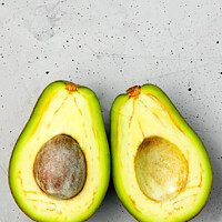 Buy canvas prints of Avocado, cut in half, one slice with a core, on a gray concrete background, top view. by Sergii Petruk