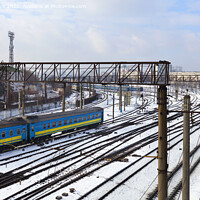 Buy canvas prints of Passenger railway wagons ride along the railway tracks in the winter season against the backdrop of the cityscape by Sergii Petruk