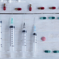 Buy canvas prints of Medical syringes, capsules, pills lie vertically on a white roughly painted wooden table. by Sergii Petruk