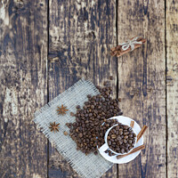 Buy canvas prints of Grain coffee in a cup, which stands on a sackcloth from burlap. Cinnamon on a platter and tied with a rope. Anise stars complement the aroma of coffee. View from above. by Sergii Petruk