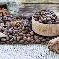Buy canvas prints of Grain coffee in a wooden cup and burlap. Cinnamon sticks are tied with string. Anise and dried slices of lemon on an old wooden board. by Sergii Petruk