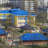 Buy canvas prints of Bright blue roof of kindergarten against the background of gray urban high-rise buildings by Sergii Petruk