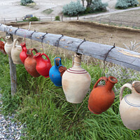 Buy canvas prints of The multi-colored clay pots of desires hang tied on a wooden crossbar in Cappadocia. by Sergii Petruk